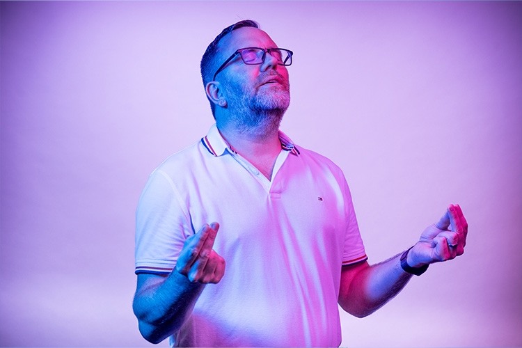 Man has his eyes closed and holds his hands in front of him 